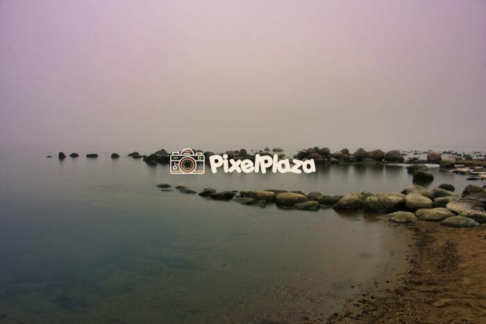 Foggy Shoreline with Tranquil Waters and Rocks Foggy Shoreline with Tranquil Waters and Rocks