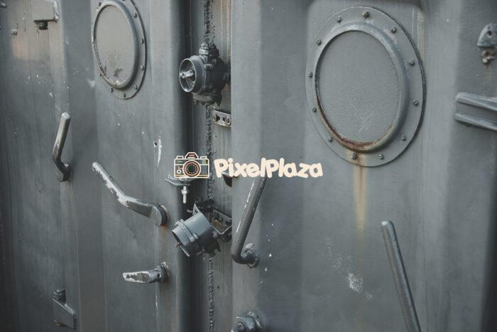 Close-Up of Heavy Steel Ship Doors with Portholes and Mechanical Levers
