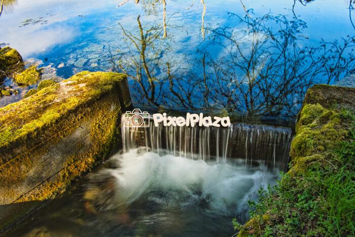 Tranquil Stream Waterfall with Moss-Covered Stone and Reflections