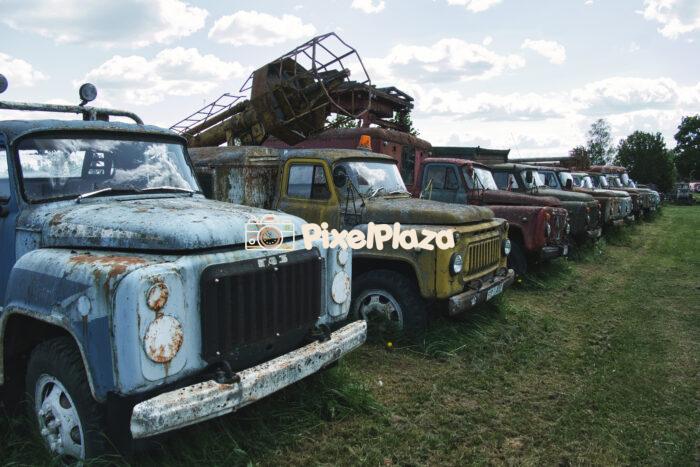 Row of Abandoned Soviet Trucks in a Rural Field - Vintage Industrial Decay