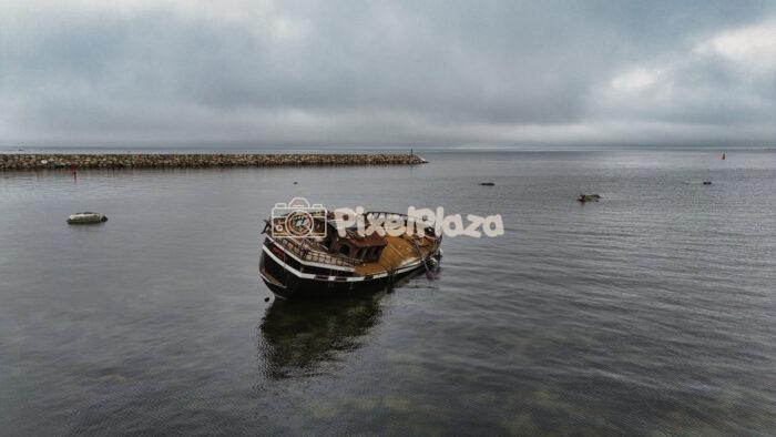 Abandoned Shipwreck in Baltic Sea Harbor Under Cloudy Sky