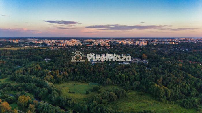 Aerial Panorama of City Skyline and Green Forest at Sunset