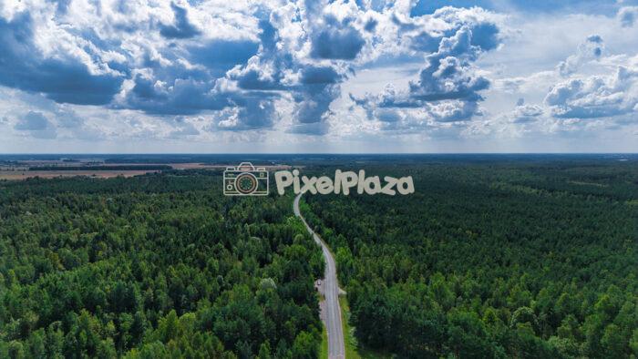 Scenic Drone View of Winding Road Through Dense Green Forest Under Dramatic Cloudy Sky2 Scenic Drone View of Winding Road Through Dense Green Forest Under Dramatic Cloudy Sky