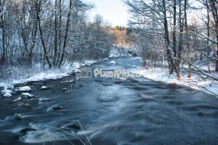 Scenic Winter River Flowing Through Snow-Covered Forest in Estonia