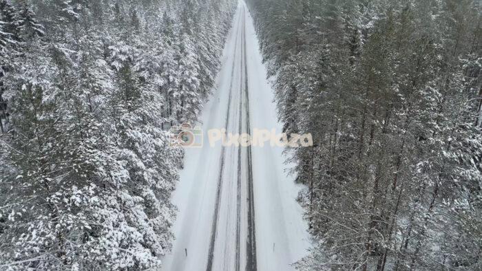 Winter Forest Road in Estonia - Aerial Drone View with Passing Cars