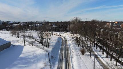 Aerial Drone View of Tram Passing Through Snowy Tallinn Cityscape in Winter, Estonia