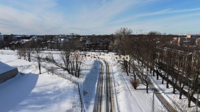 Aerial Drone View of Tram Passing Through Snowy Tallinn Cityscape in Winter, Estonia