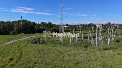 4K aerial drone video of high voltage power line pylon in a green field