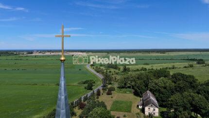 Drone view of Jõelähtme church spire golden cross over scenic green fields