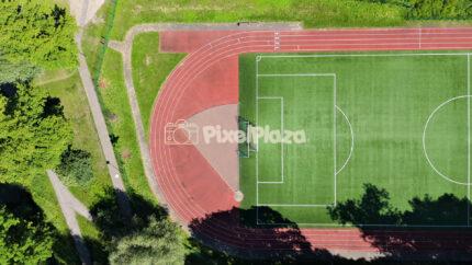 Top down drone shot of green football field and red running track stadium