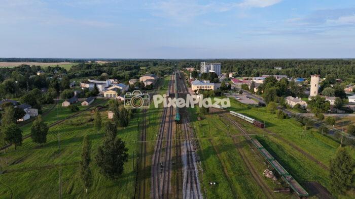 Aerial shot panning over rural train station and railway tracks